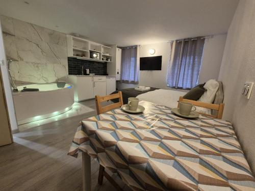 d'un salon avec une table et d'une chambre avec une salle de bains. dans l'établissement Studio de Charme avec Jacuzzi - Escapade Relaxante, à Strasbourg