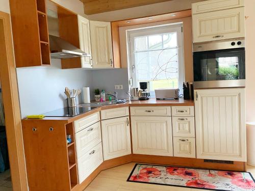 a kitchen with white cabinets and a sink and a window at Haus am See Ferienhaus 4 in Wackersdorf