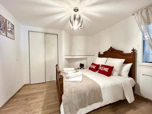 a bedroom with a bed with red pillows and a chandelier at Le Chavanna - Terrasse Parking - CLG Savoie in Saint-Pierre-dʼAlbigny