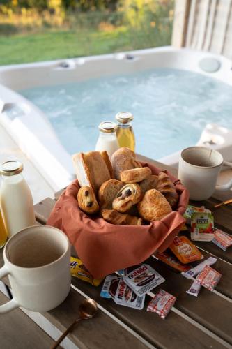 Ein Korb mit Gebäck und Kaffee stand auf einem Tisch neben einem Pool. in der Unterkunft DAMONA LODGES in Vairé