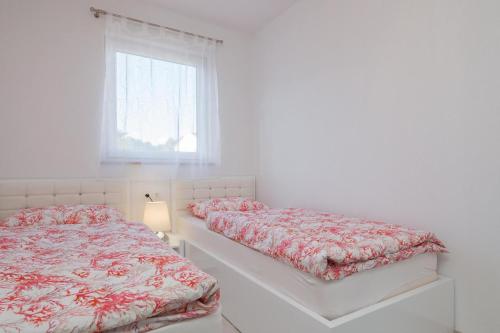 a white bedroom with two beds and a window at La Perla apartments 3 in Sutivan
