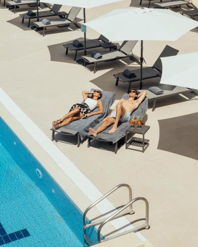 two people laying on lounge chairs next to a swimming pool at Grand Hotel Telese in Telese