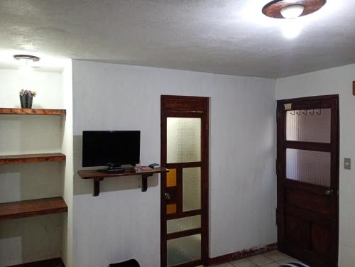 a room with a television and a door with a window at Hotel Casolia in Quetzaltenango