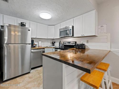 a kitchen with white cabinets and a stainless steel refrigerator at Enchanting 2-Bedroom Ground Floor Beach Condo at Cape Canaveral WiFi & AC in Cape Canaveral