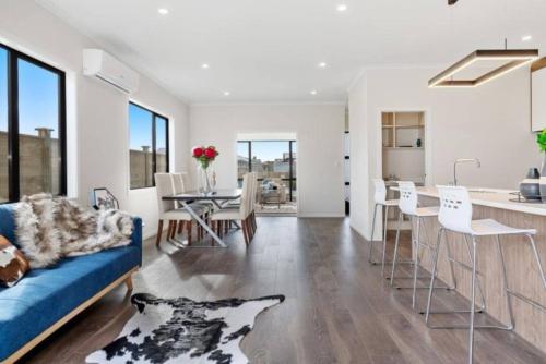 a living room with a blue couch and a table at Modern Beach Retreat 4 bedrooms in Papamoa