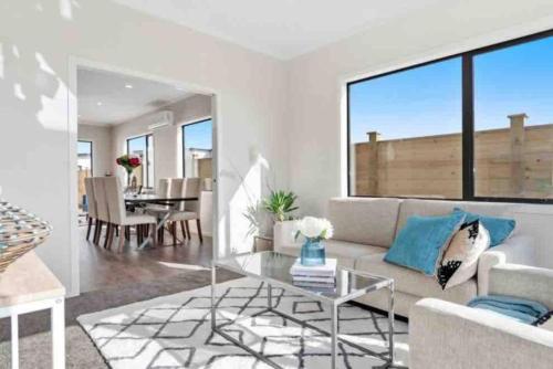 a living room with a couch and a glass table at Modern Beach Retreat 4 bedrooms in Papamoa