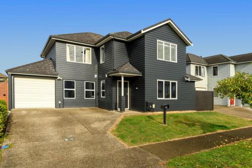 una casa negra con un garaje blanco en Spacious home on landing drive, en Tauranga