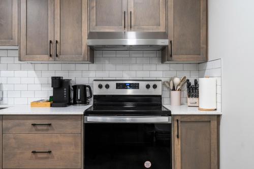 a kitchen with a black stove and wooden cabinets at Private Lower Suite, Sleeps 4, Queen Bed, Netflix, Parking in Balzac