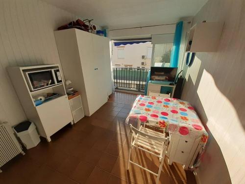 une petite pièce avec une table et une cuisine dans l'établissement AS18262 - Studio en Centre Ville, au Grau-du-Roi