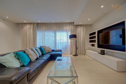 a living room with a couch and a flat screen tv at Tigne Seafront 3BR Escape with Mesmerising Views by 360 Estates in Il-Gżira taʼ Forti Manoel