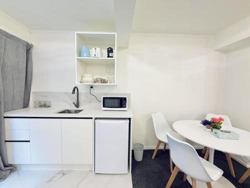 a white kitchen with a sink and a table at Unit 6 Fenton Sumner Lodge in Rotorua