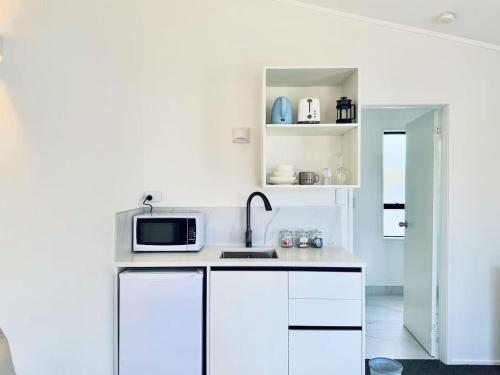 a white kitchen with a sink and a microwave at Unit 4 Fenton Sumner Lodge in Rotorua