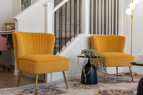 two yellow chairs in a living room with a staircase at 3 Bedroom Detached Home with Free Parking, Netflix, Free Banff Pass, King Size Bed & Portable AC in Balzac