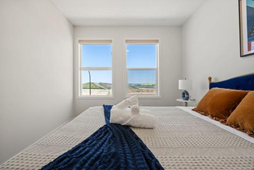 a white bedroom with a large bed with two windows at 3 Bedroom Detached Home with Free Parking, Netflix, Free Banff Pass, King Size Bed & Portable AC in Balzac