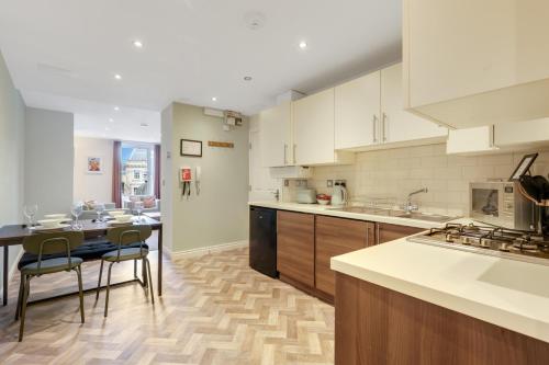 a kitchen with white cabinets and a table and chairs at Earl Grey at The Tea Warehouse - North East Escapes in Alnwick