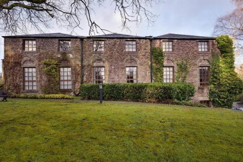a large brick building with a grass field in front of it at The Mill Retreat in Stirling