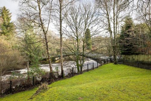 a fence in front of a river with a bridge at The Mill Retreat in Stirling