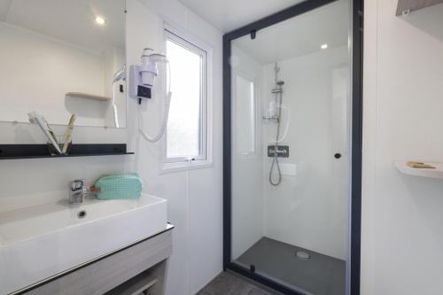 Un baño blanco con ducha y lavabo. en Camping La Davière Plage - Maeva, en Saint-Jean-de-Monts
