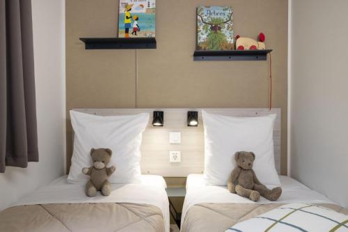 dos ositos de peluche sentados en dos camas en una habitación en Camping La Davière Plage - Maeva, en Saint-Jean-de-Monts