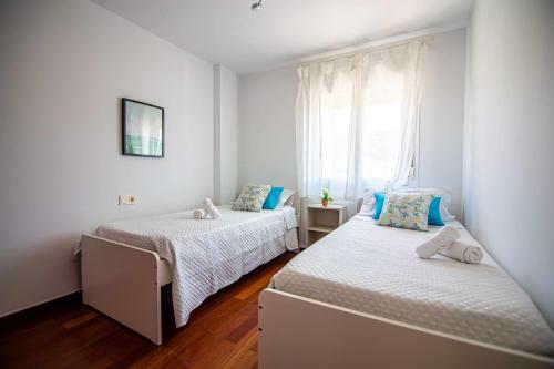 dwa łóżka w małym pokoju z oknem w obiekcie Villa Cañada torremolinos w mieście Torremolinos