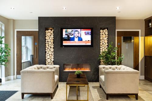a living room with a fireplace and a tv on a wall at Rock Mill 1 Bed Apartment 15 in Stoney Middleton