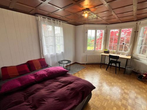 a bedroom with a bed and a desk and windows at Chaletwohnung im Luzerner Seetal mit Platz, Charm und Erholungswert in Ballwil