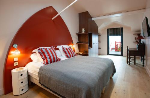 a bedroom with a large bed with a red headboard at Hôtel Kemaris in Biarritz