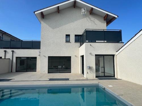 un bâtiment avec une piscine en face d'une maison dans l'établissement Maison 70 avec 8 chambres lechaffardcom, à Satolas-et-Bonce