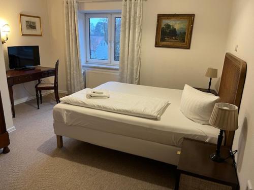 a bedroom with a bed with a desk and a window at Hotel & Restaurant Raueneck in Bad Saarow