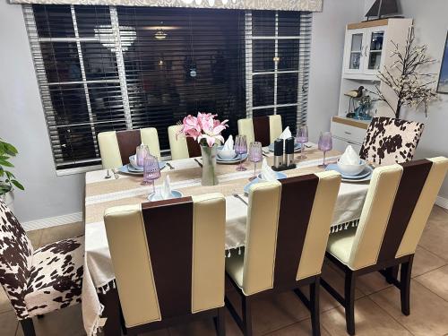 a dining room with a table and chairs with flowers at South Florida Spacious Oasis 4BR Retreat with 2 King Beds, Amazing Pool, near Beaches in Deerfield Beach
