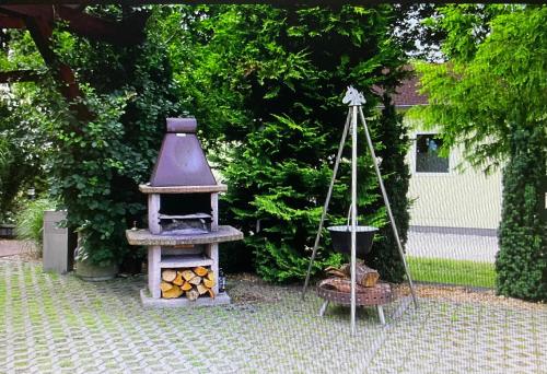 a garden with a grill and a pile of logs at Pension zum Reiterhof, 3-Bettzimmer in Schmogrow