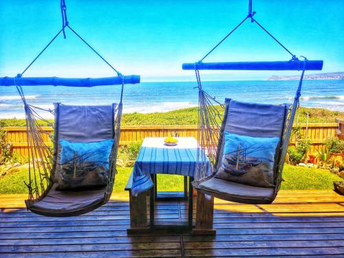 two chairs and a table on a deck with the ocean at Whalecome - Witsand Beachfront House in Witsand