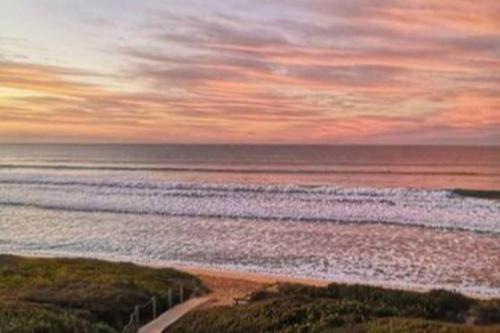 a view of a beach with the ocean at sunset at Whalecome - Witsand Beachfront House in Witsand