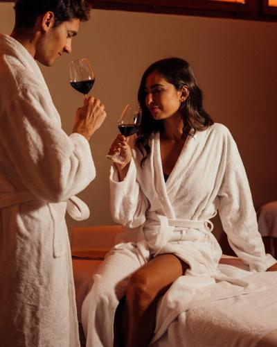 a man and a woman sitting on a bed drinking wine at Grand Hotel Telese in Telese