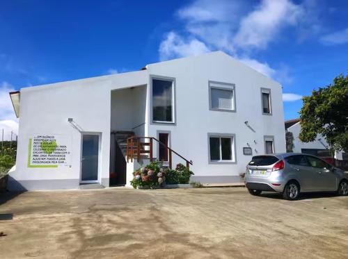 a white house with a car parked in front of it at Green and Blue Cottage - Green Room in Ribeira Grande