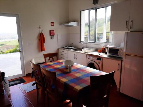a kitchen with a table and a kitchen with a refrigerator at Green and Blue Cottage - Green Room in Ribeira Grande