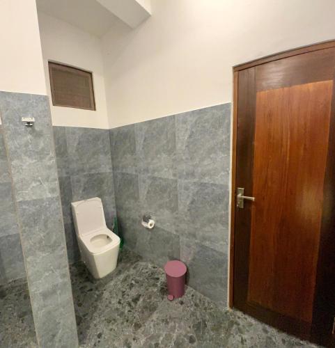a bathroom with a toilet and a wooden door at Vibe Ella in Ella