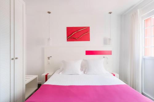 a white bedroom with a pink and white bed at Hôtel Kemaris in Biarritz