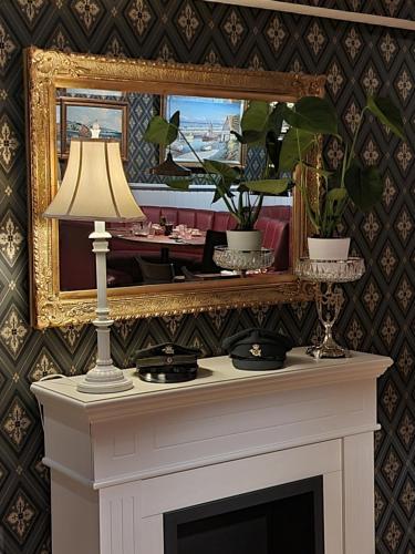 a fireplace with a mirror and a lamp on it at Det Gamle Posthus in Rønne