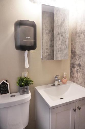 a bathroom with a toilet and a soap dispenser on the wall at Queen Suite - Private Entrance - WiFi in Morrow