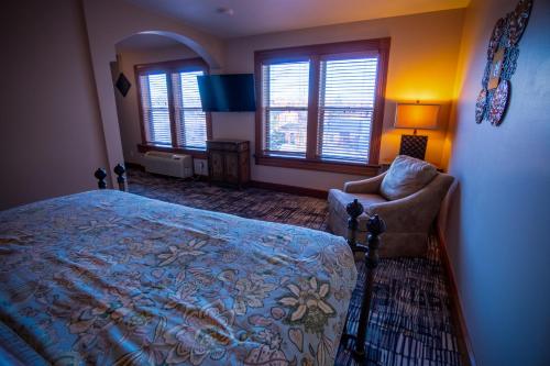 a bedroom with a bed and a chair and windows at Nuk's Executive Suites in De Pere