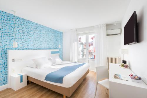 a bedroom with a bed with a blue accent wall at Hôtel Kemaris in Biarritz