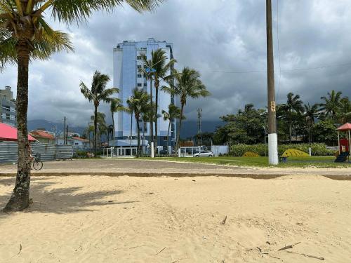 a beach with palm trees and a tall building at Helbor Atlantis by Doce Lar de Bertioga in Bertioga