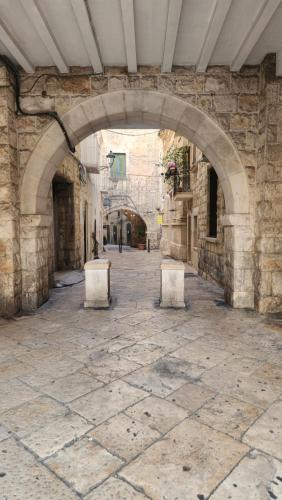 an alley with two benches in a stone building at La Maison De Poupée in Bari
