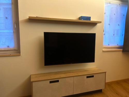 a flat screen tv on a wall with two windows at Casa Franz in Tesero
