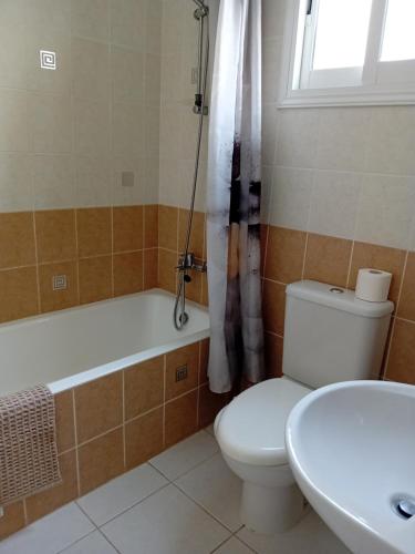a bathroom with a toilet and a tub and a sink at Tala Gardens Apartment in Tala