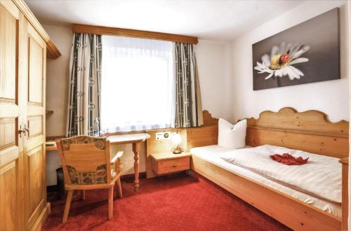 a bedroom with a bed and a desk and a window at Hotel Metzgerwirt in Kirchberg in Tirol