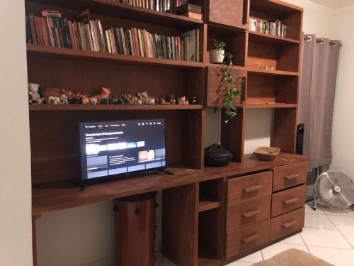 a wooden desk with a computer on top of it at Apartamento com Wifi, Livros e Espaço Pet in Rio das Ostras