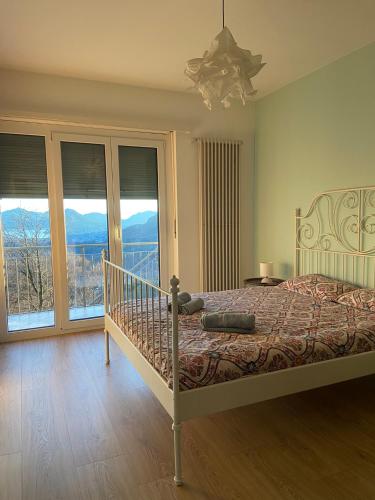 a bedroom with a bed and a balcony with mountains at Casa Cristina in Roveredo Capriasca