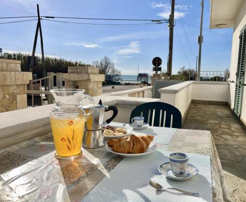 a table with a plate of food and a glass of orange juice at Front Beach Apartments Rose Superiore in Marina di Pescoluse